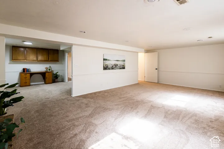 Spacious interior featuring wall-to-wall carpeting, chair rail molding, recessed lighting, and built-in wood cabinetry