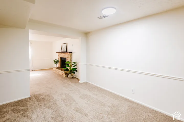Neutral interior featuring wall-to-wall carpeting, chair rail molding, and a brick fireplace with a wood mantel
