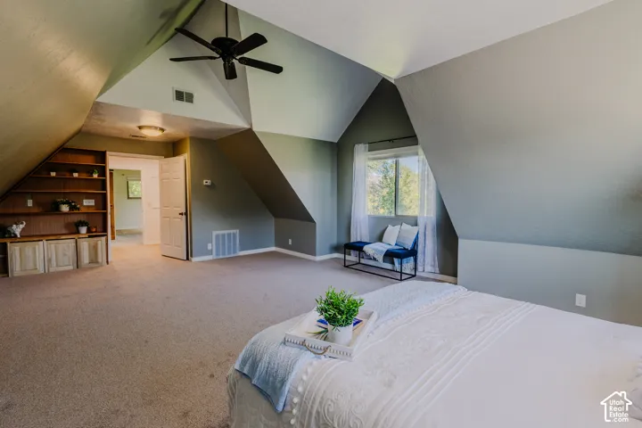 Vaulted ceilings with architectural angles, built-in wooden shelving, and a ceiling fan
