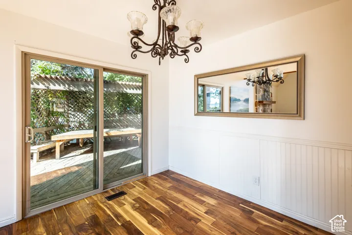 Wood-finish flooring, white beadboard wainscoting, sliding glass door, and traditional iron chandelier