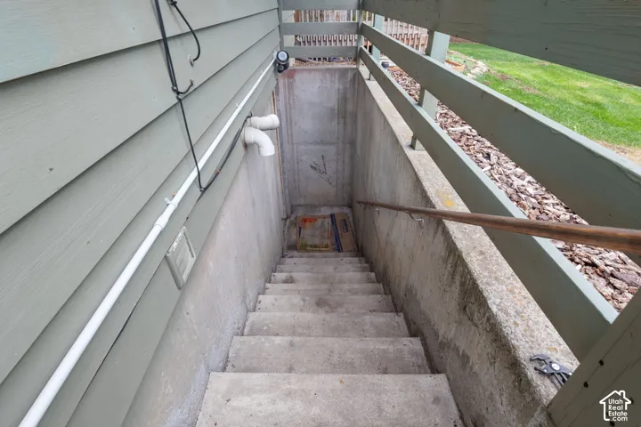 Exterior concrete stairwell with wood-finish horizontal siding and a secured handrail