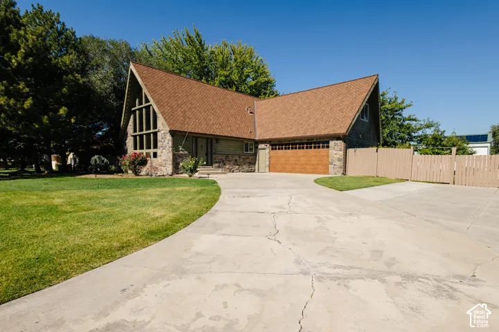 A-frame style exterior featuring stone masonry, vertical siding, a multi-pane floor-to-ceiling window, and an attached two-car garage with a wood-finish door