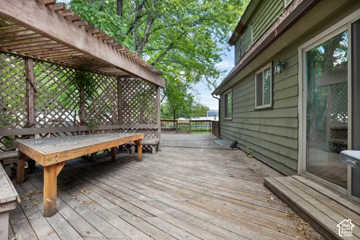 Expansive wood deck featuring a built-in pergola with lattice side panels and exterior siding