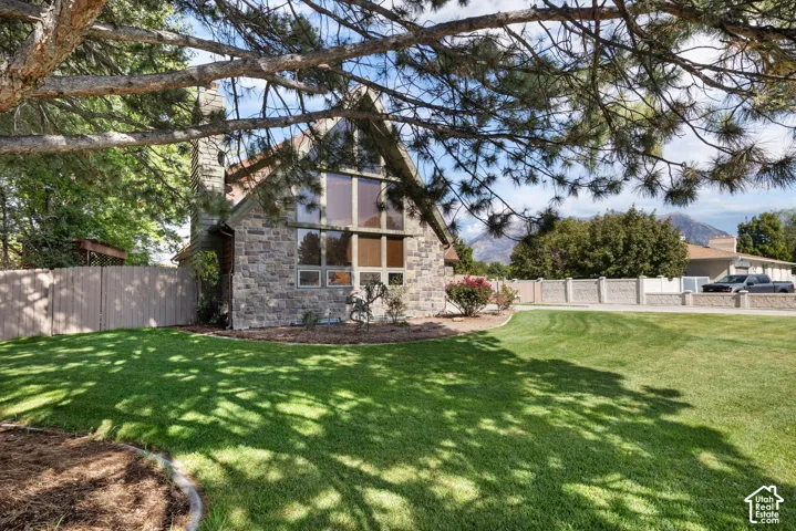 A-frame exterior featuring stone masonry, expansive multi-panel windows, and a stone-clad chimney, set against a manicured lawn