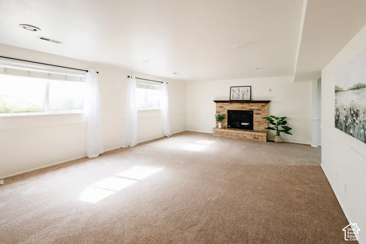 Spacious interior featuring neutral carpeting, a brick masonry fireplace, recessed lighting, and wall wainscoting