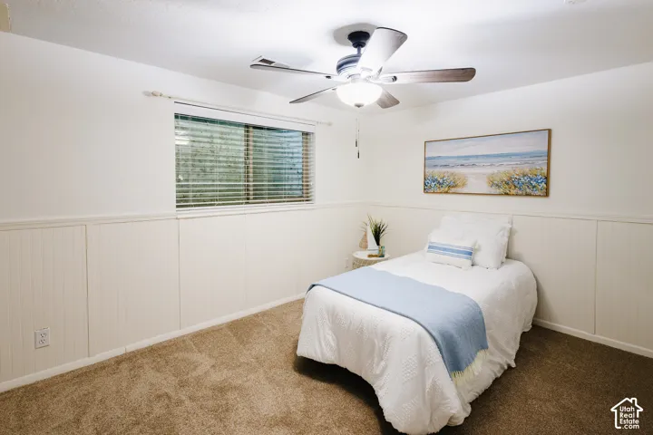 Room featuring wall-to-wall carpeting, vertical beadboard wainscoting, sliding window with horizontal blinds, and ceiling fan with integrated lighting