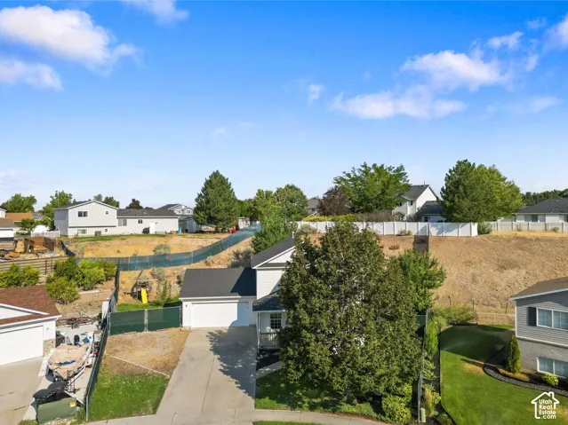 Two-story residence featuring a shingled roof, attached two-car garage, concrete driveway, and mature landscaping
