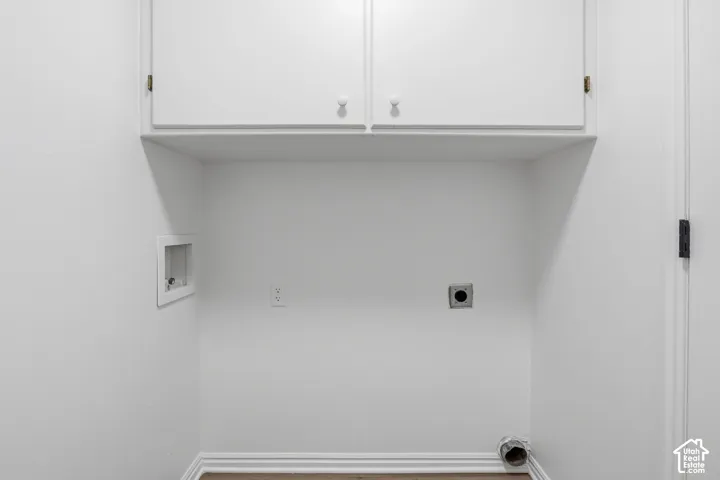 Utility area featuring white built-in upper cabinetry and dedicated hookups for laundry appliances