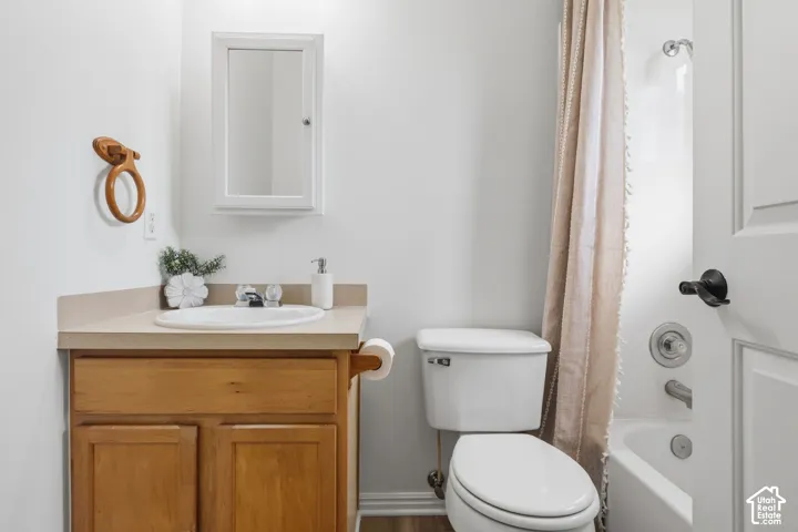 Bathroom featuring a wood-finish vanity with a solid-surface countertop, integrated basin, wall-mounted medicine cabinet, and a combined tub and shower enclosure with chrome fixtures