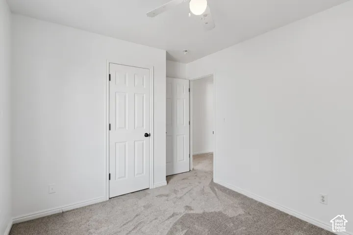 Room featuring neutral carpeting, white interior doors with matte black hardware, and a ceiling-mounted light fixture with an integrated fan