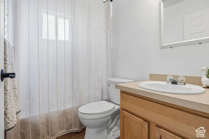 Bathroom featuring a vanity with light-tone wood cabinetry, a solid-surface integrated sink and countertop, and a white-framed wall mirror