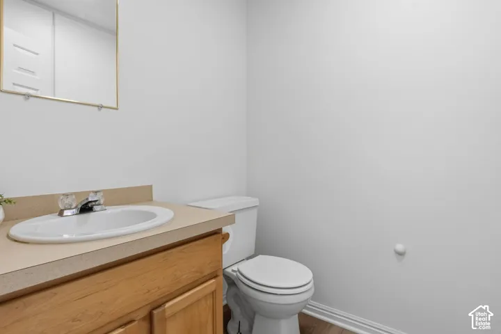 Wood-finish vanity cabinet, solid-surface countertop with integrated oval sink, dual-handle faucet, wall-mounted rectangular mirror, and two-piece elongated toilet