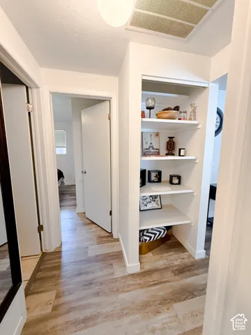 Built-in recessed shelving unit with white finish, wood-finish flooring, and solid-core interior doors