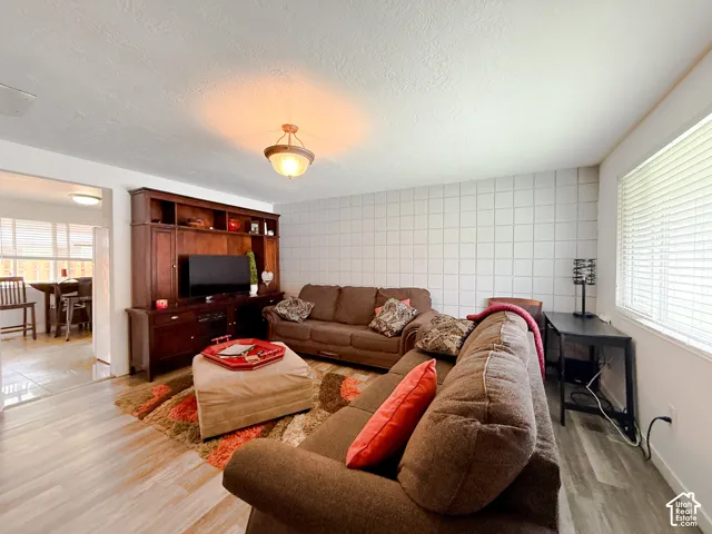 Living area featuring wood-finish flooring, a floor-to-ceiling grid-pattern tile accent wall, and a large built-in wood media console