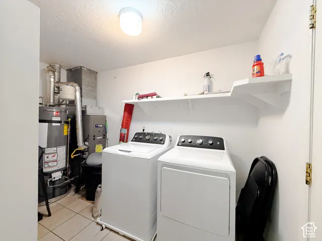 Utility space featuring tile flooring, built-in shelving, and direct access to water heater and furnace units
