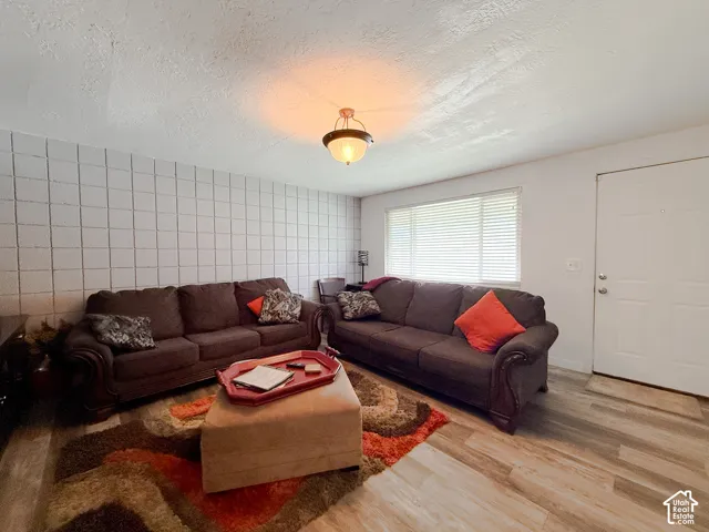 Interior space featuring a textured cinder block accent wall, wood-finish flooring, and a semi-flush mount ceiling fixture