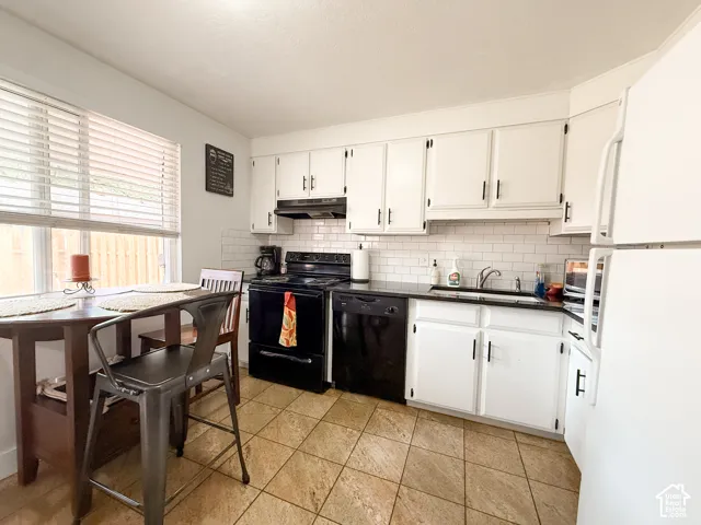 Kitchen featuring white cabinetry with dark hardware, subway tile backsplash, dark solid-surface countertops, and tile flooring