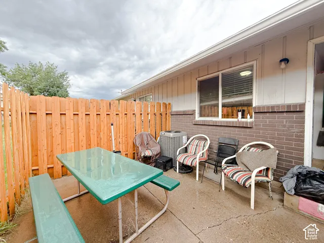 Concrete patio with vertical wood-paneled siding, brick masonry exterior, and a cedar-tone wood privacy fence