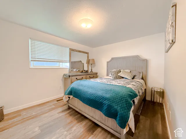 Room featuring wood-finish flooring, white walls, and a horizontal window with attached blinds, completed by a flush-mount ceiling fixture