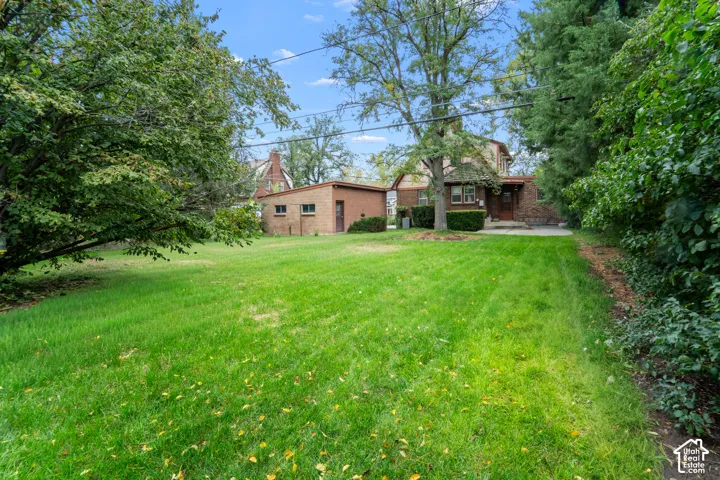 Expansive backyard featuring a level lawn, mature trees, brick exterior construction, and a detached brick garage