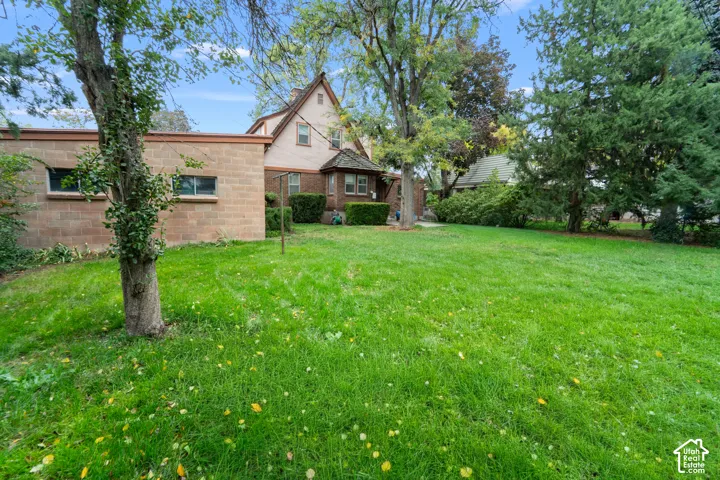 Expansive lot featuring mature trees, a multi-textured exterior of brick and masonry, and a pitched roofline