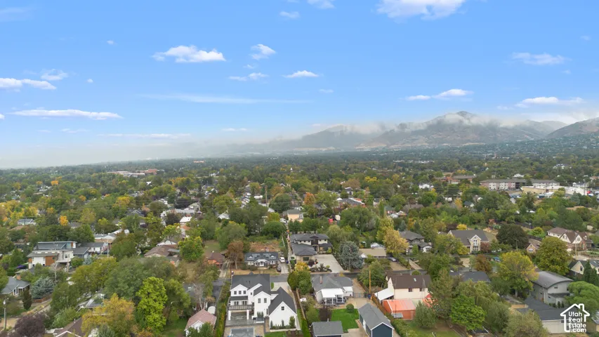 Aerial perspective of the residential property featuring mountain scenery, mature tree canopy, and established neighborhood infrastructure