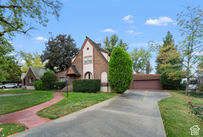 Brick exterior featuring a steep-pitched roofline, a decorative front-facing gable, a concrete driveway, and an attached garage