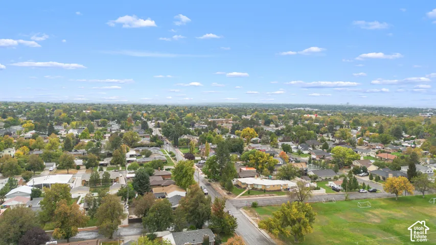 Aerial perspective of the residential area featuring mature trees, established landscaping, and an expansive grass field