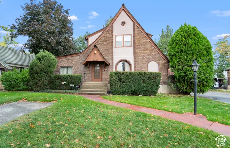Tudor-style exterior featuring a brick facade, arched window detailing, steep roof pitch, covered entryway, and concrete steps