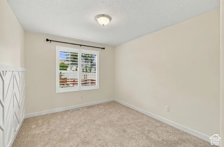 Neutral-toned interior space featuring herringbone-pattern wall paneling, carpeting, and plantation shutters