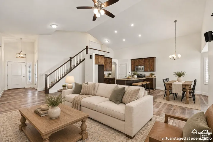 Vaulted ceilings, wood-finish flooring, recessed lighting, staircase with wooden handrail, and kitchen cabinetry with integrated appliances