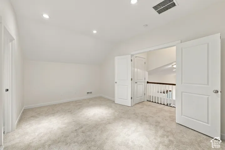 Neutral-toned interior featuring recessed lighting, high-pile carpeting, paneled interior doors, and a staircase with a wooden handrail