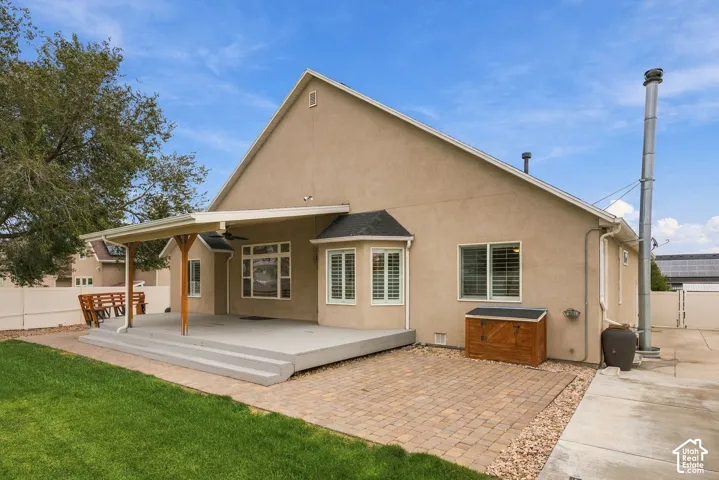 Stucco exterior featuring a covered patio, multi-level composite decking, paver patio, and lawn area