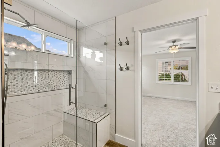 Walk-in shower featuring large-format wall tile, glass enclosure, built-in tiled bench, stone-finish mosaic inlay, and rain-style shower head