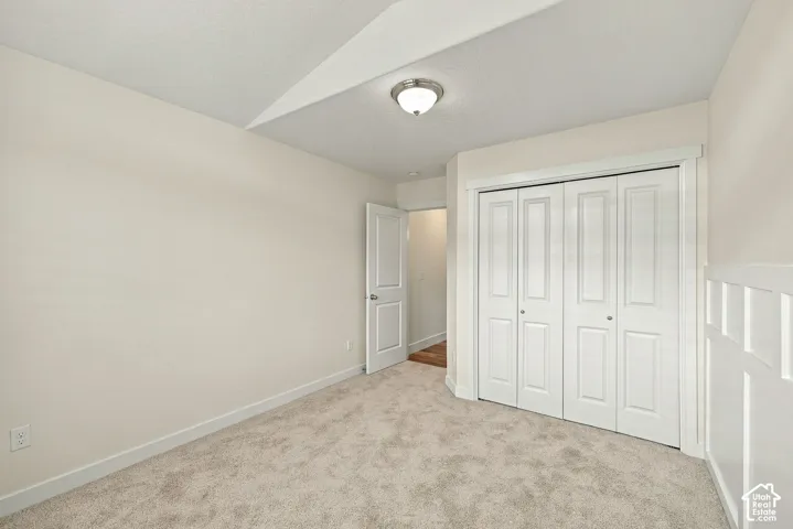 Vaulted ceiling, wall-to-wall carpeting, bi-fold closet doors, and wainscoting detail