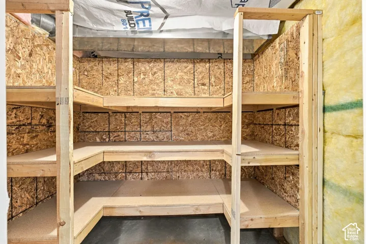 Dedicated storage area featuring built-in, multi-level wooden shelving and exposed structural framing