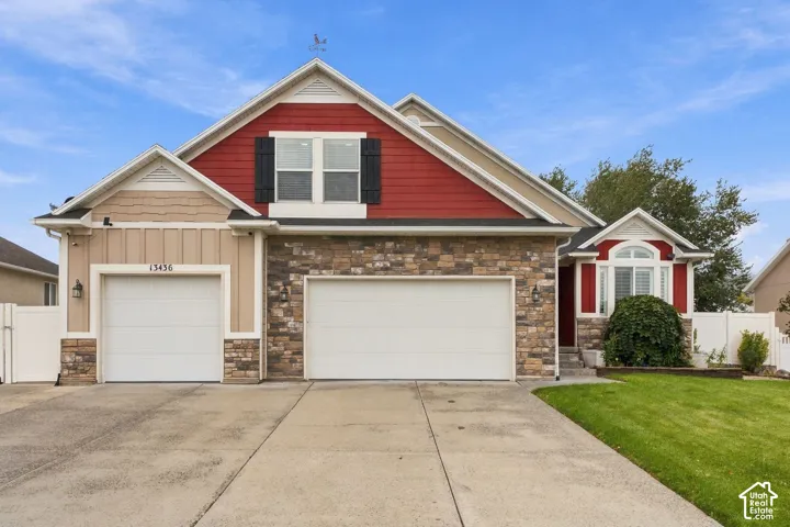 Multi-gabled exterior featuring horizontal siding, shake-style accents, stone veneer masonry, and a three-car garage