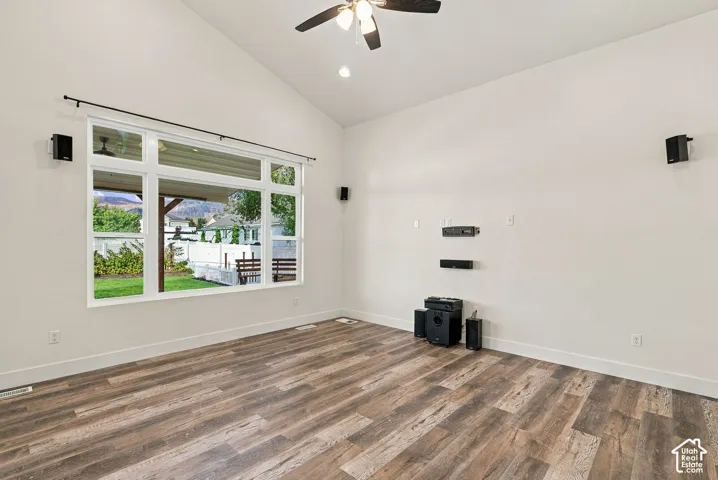 Vaulted ceilings, large multi-pane window, wood-finish flooring, and ceiling fan