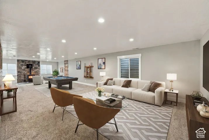 Spacious room featuring neutral carpeting, recessed ceiling lighting, and a floor-to-ceiling stone fireplace with a wood-burning stove