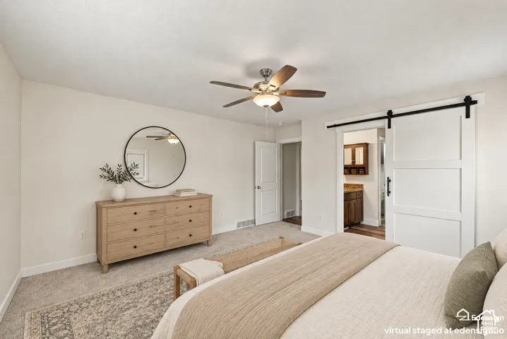 Interior space featuring neutral-toned carpeting, a ceiling-mounted light fixture with fan, and a white sliding barn-style door with black metal hardware