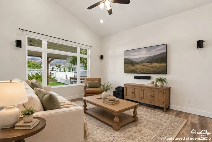 Vaulted ceilings, expansive multi-pane window, wood-finish flooring, and ceiling fan with integrated lighting