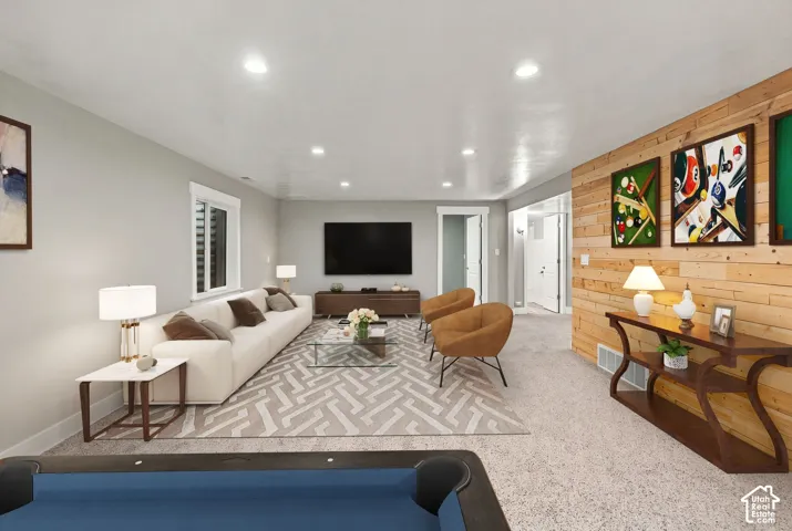 Living area featuring horizontal wood-plank accent wall, recessed lighting, and carpeted flooring