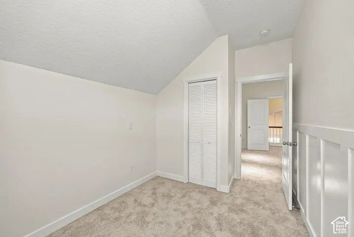 Sloped ceiling, louvered bi-fold closet doors, and wainscot wall paneling