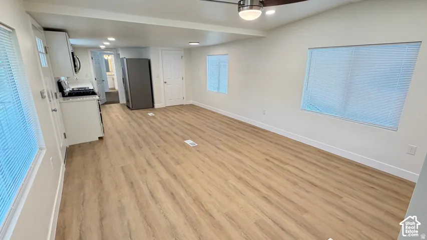 Open-concept interior featuring wood-finish flooring, recessed lighting, a ceiling fan, and multiple windows with horizontal blinds