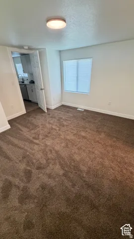 Interior room featuring neutral wall paint, wall-to-wall carpeting, a single-window pane with blinds, and a flush-mount overhead light fixture