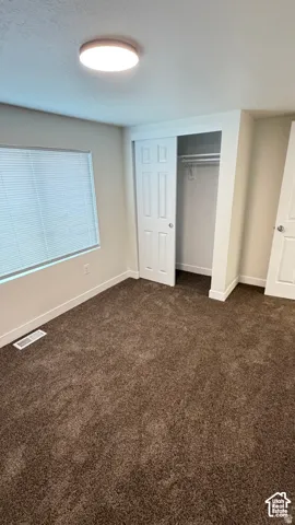 Neutral-toned room featuring plush wall-to-wall carpeting, recessed flush-mount overhead lighting, a sliding-door closet, and a multi-pane window with installed blinds