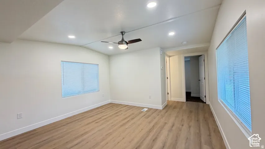 Vaulted ceilings, wood-finish flooring, recessed lighting, and a modern ceiling fan with an integrated light fixture