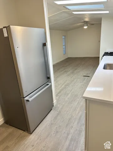 Kitchen featuring stainless steel refrigerator, white countertops, wood-finish flooring, recessed lighting, and ceiling fan