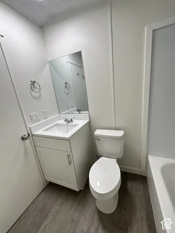 Bathroom featuring a white vanity cabinet, square undermount sink, flat-panel mirror, and wood-finish flooring