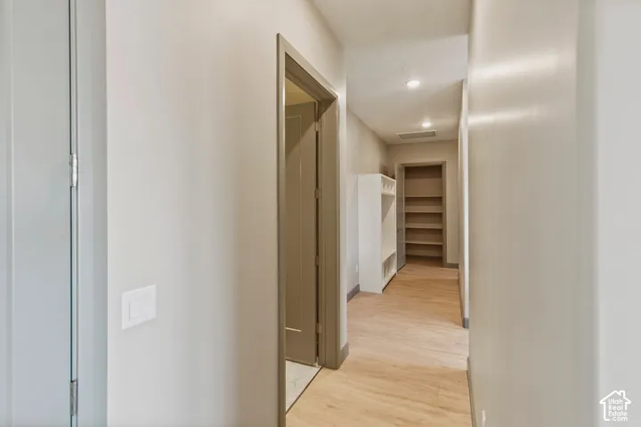 Hallway featuring wood-finish flooring, recessed lighting, a built-in locker storage unit, and an open-concept walk-in pantry with integrated shelving